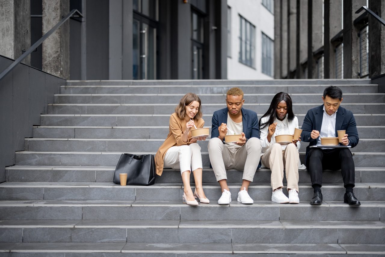 A group of people sitting on steps looking at their phones.