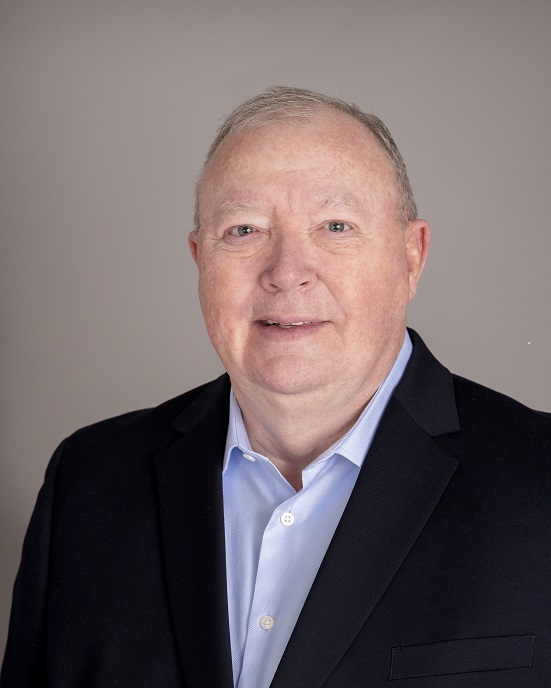 A man in a suit and shirt is smiling.